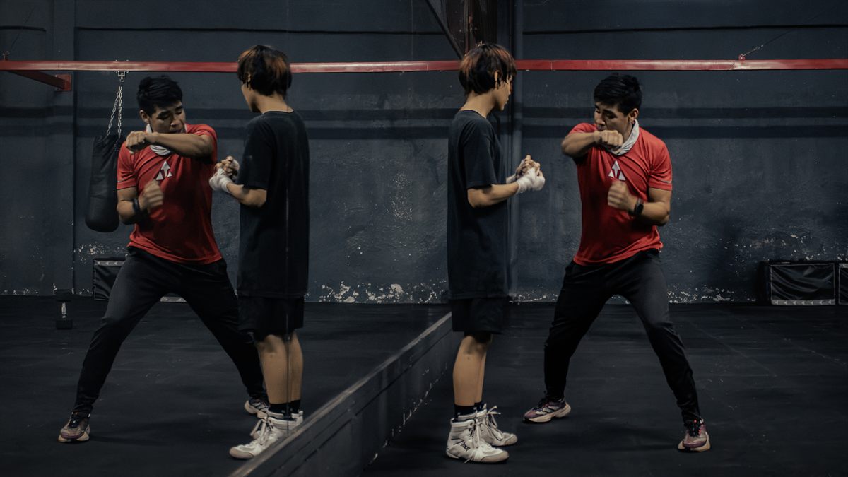Boxing coach teaching technique in front of a mirror
